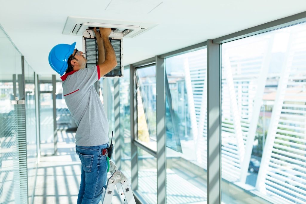 Technician testing a ceiling-mounted HVAC unit